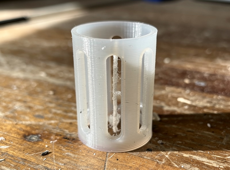 Close-up of a 3D-printed PETG reservoir insert showing wick channel and overflow slots