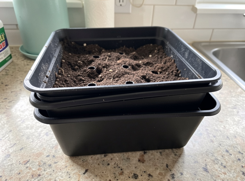 Two stacked 1020 trays showing the drain-hole grow tray nested in a solid bottom-watering tray